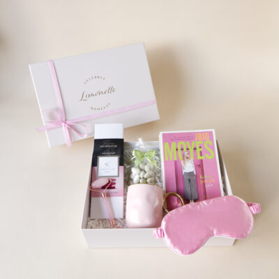 Zestaw prezentowy zawiera: Książka Kolory Pawich Piór, Opaska na oczy, różowy kubek, migdały w czekoladzie, czekolada ruby, roller do twarzy.